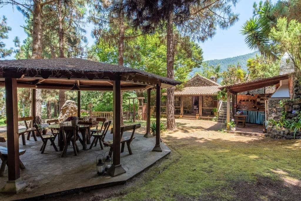 Cenador de madera con tinajas tradicionales en el jardín de la finca
