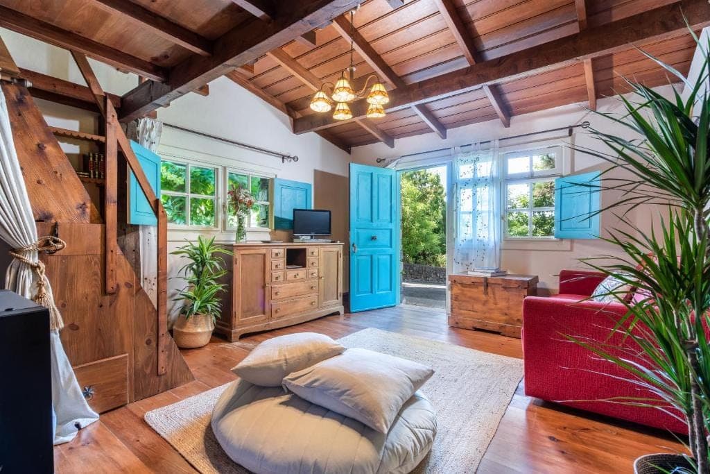 Salón de Casa Azul con carpintería azul mar, sofá rojo y plantas