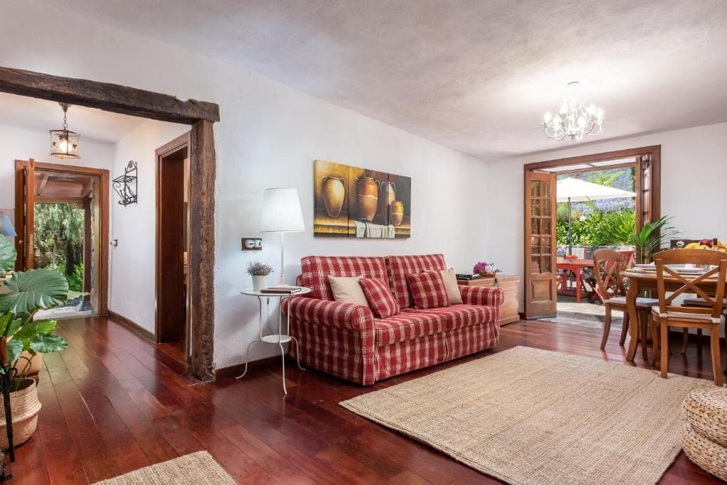 Salón de La Era con sofá de cuadros rojo y suelo de madera