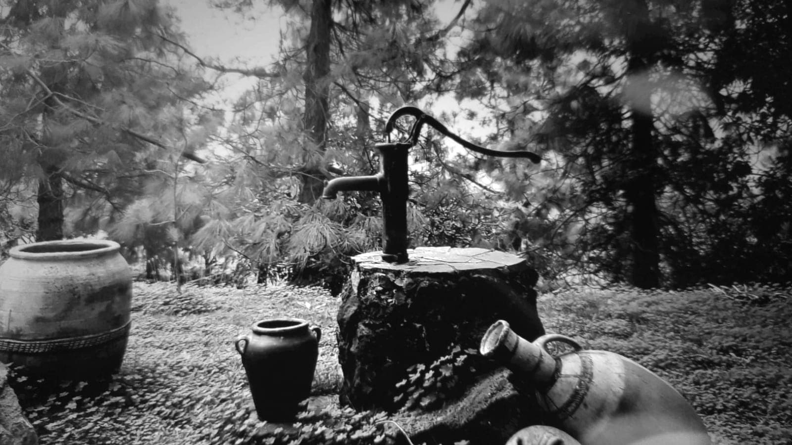 Bomba de agua manual de hierro sobre un tocón, junto a cántaros de barro, en tono sepia