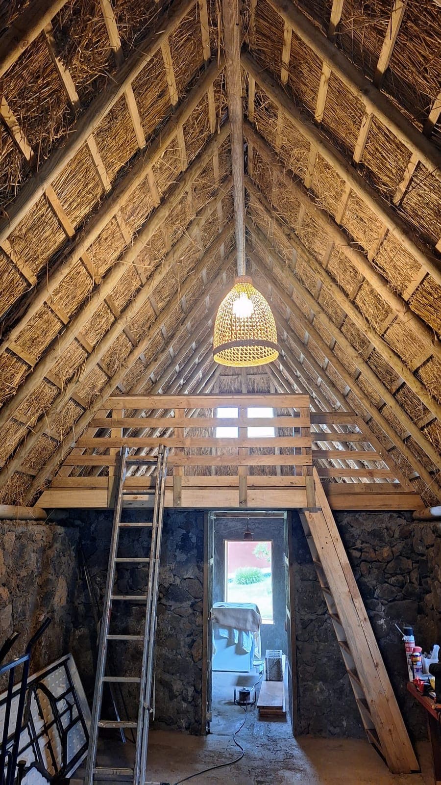 Interior del pajar bajo el techo de paja a dos aguas, con muros de piedra